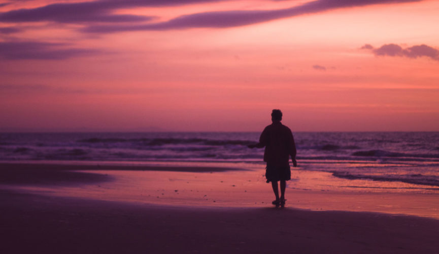 man walking on beach at sunset