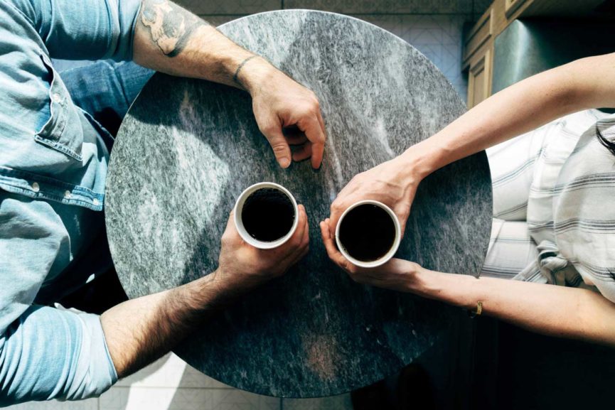 two people sitting at a table drinking coffee