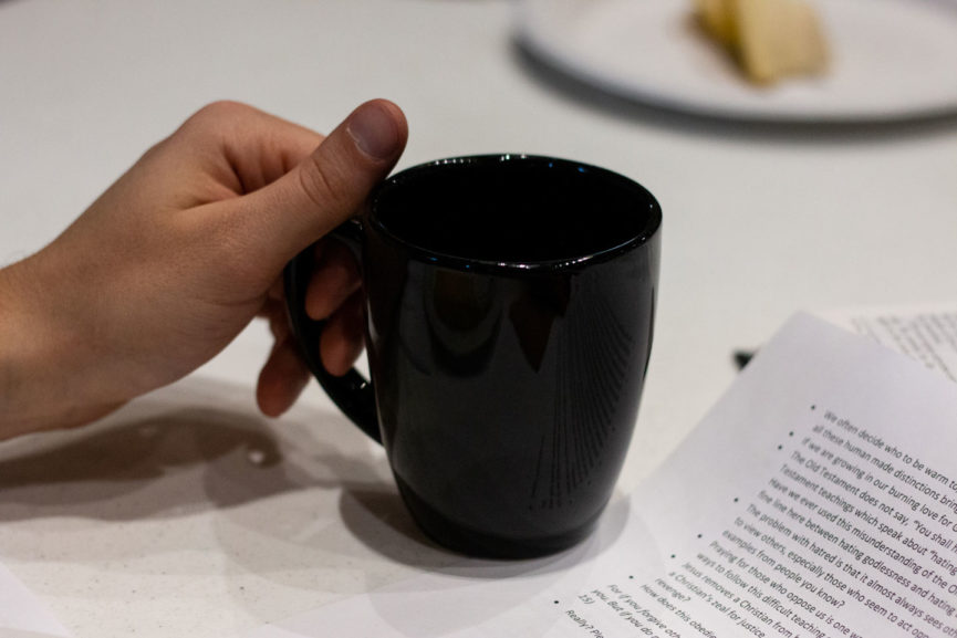 hand holding cup with a sheet of questions coffee and conversations