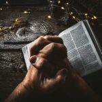 folded hands and bible
